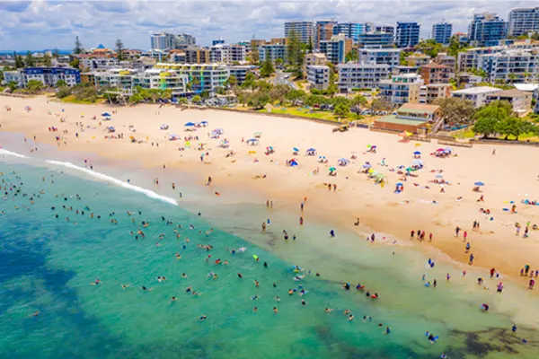 Overhead shot of Caloundra Beach with hundreds of people swimming and relaxing