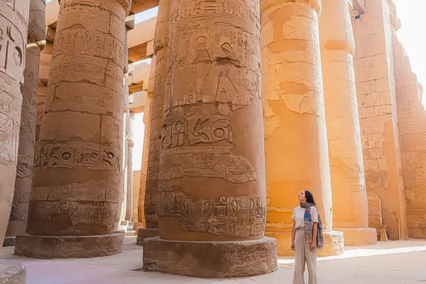 Woman standing next to large columns covered in hieroglyphics in Egypt