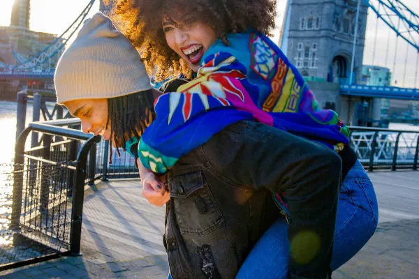 Couple piggybacking in front of the Tower Bridge in London