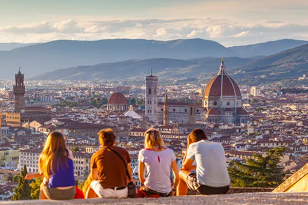 Four friends, sitting on a rooftop looking out at the city of Florence