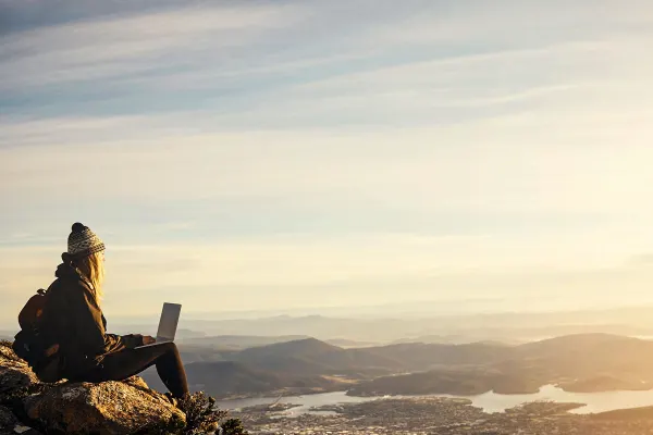A lady wearing a beanie sitting on rocks overlooking the city
