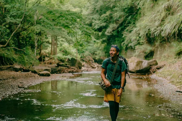 Man hiking through a river in a forest