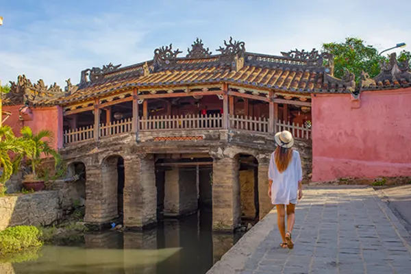 Woman looking at a pink bridge in Hoi An