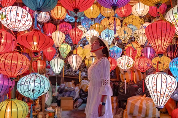 Woman in a white dress looking at dozens of multi-coloured lanterns