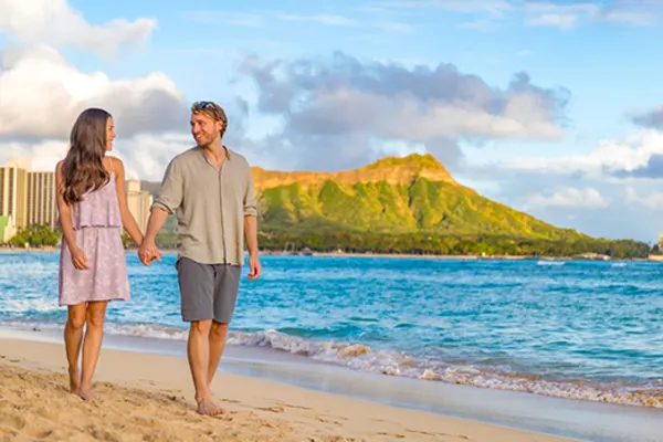 Couple walking hand in hand down a beach
