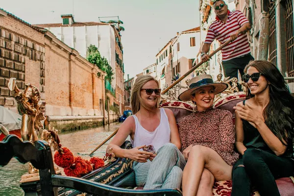 Three girls on a Gondola boat sailing down a canal