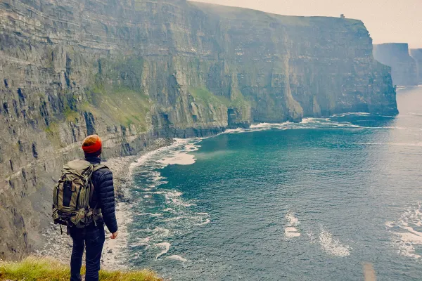 Backpacker looking out at cliffs along the coast of Ireland