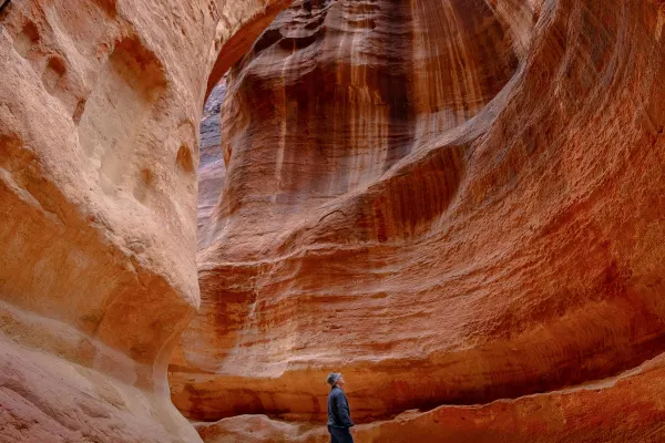 Wide shot of a man looking up at tall, worn rocks
