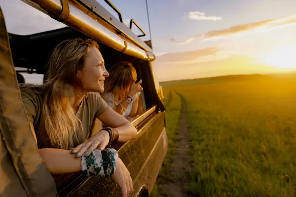 Women leaning out of a safari truck watching a sunset