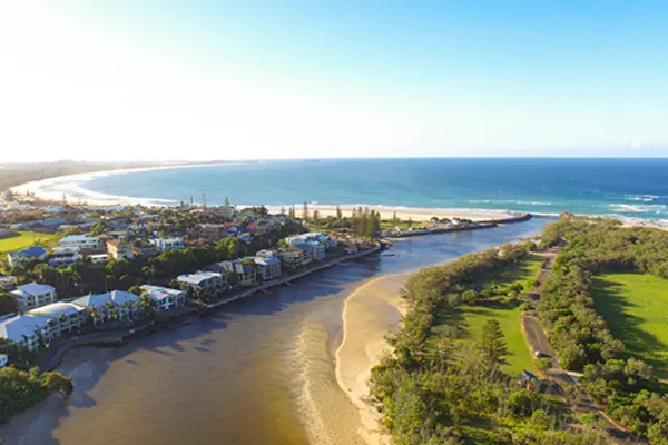 river with houses along shore connecting to the beach in kingscliff