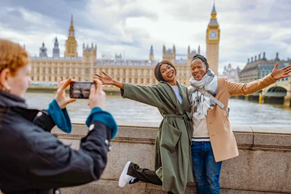 Two women posing for a picture with London's Parliament building in the background