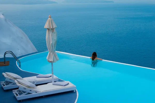 Woman relaxing in an infinity pool looking out at the ocean