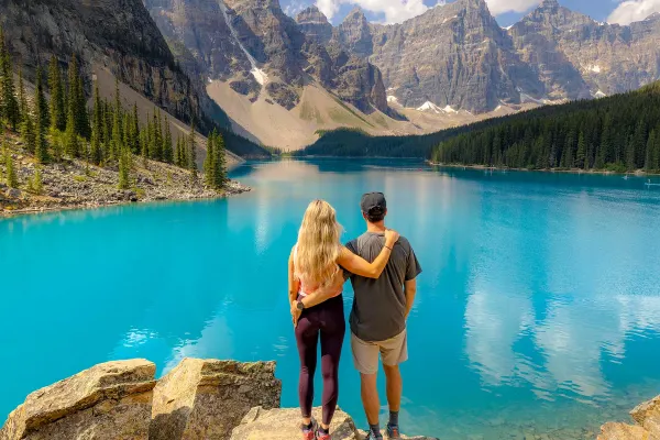 Couple arm in arm looking at a clear blue lake