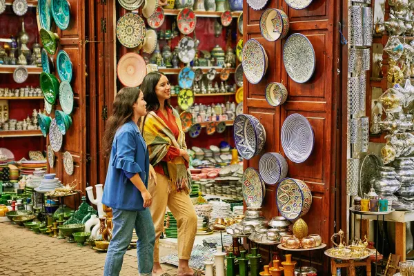 Two women looking at hundreds of colourful bowls and plates at a marketstall