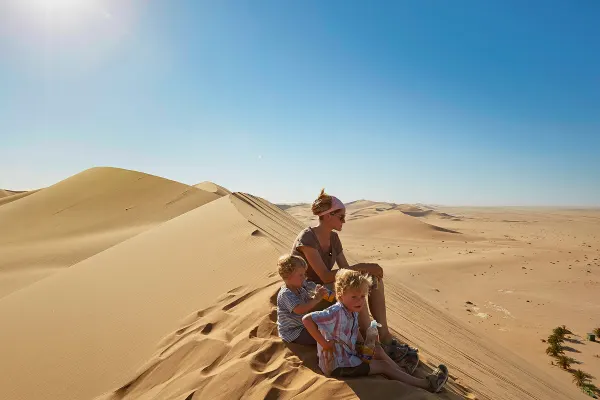 Mother and two children sitting on sand dunes