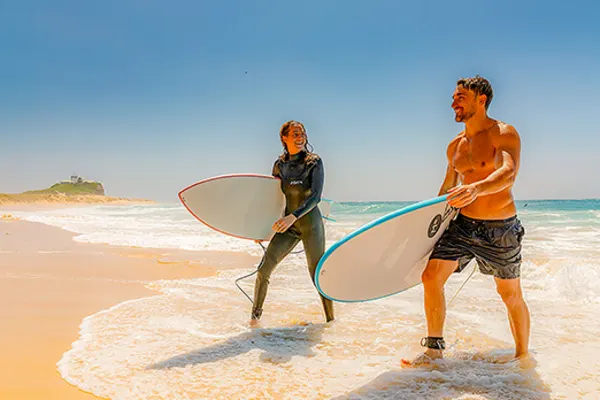 Two surfers carrying surfboards walking out of the surf
