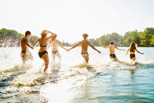 Teenagers splashing into a lake in the early afternoon