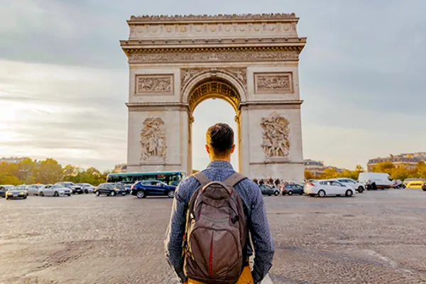 man standing across the road from large statue in paris