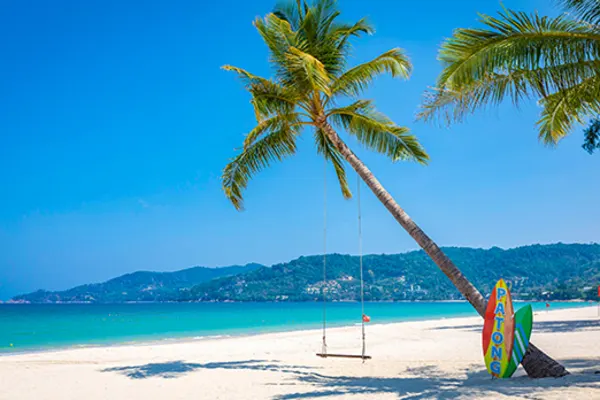 white sand beach in patong with swing hanging from tree