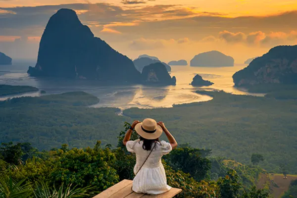 lady sitting on edge of cliff overlooking mountains in phuket