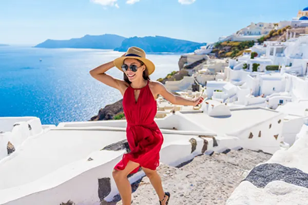 Woman in a red dress running through Santorini on a sunny day