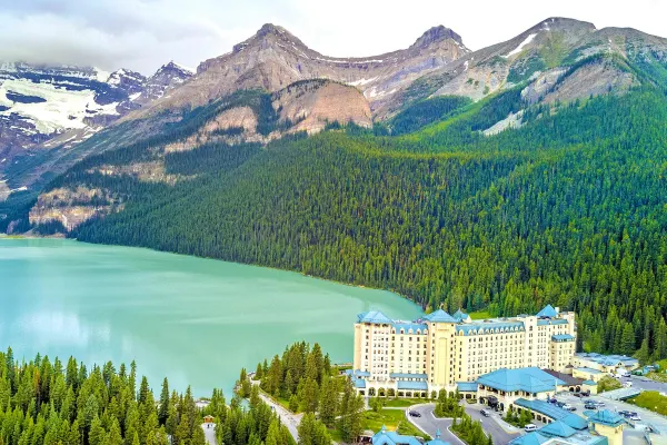 Wide shot of a hotel in a pine forest alongside a large lake