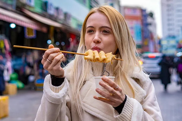 woman eating fish cake on street in seoul