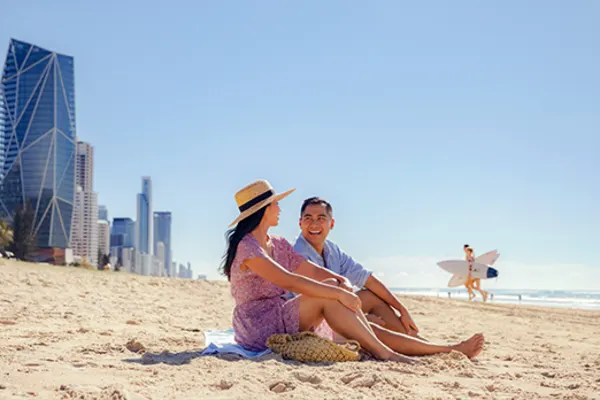 Couple smiling, sitting on a beach at Surfer's Paradise, Australia