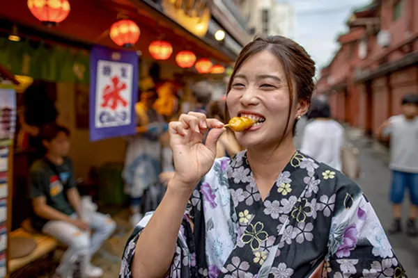 Woman smiling, eating Dango (dumpling on a stick) in Asakusa, Tokyo