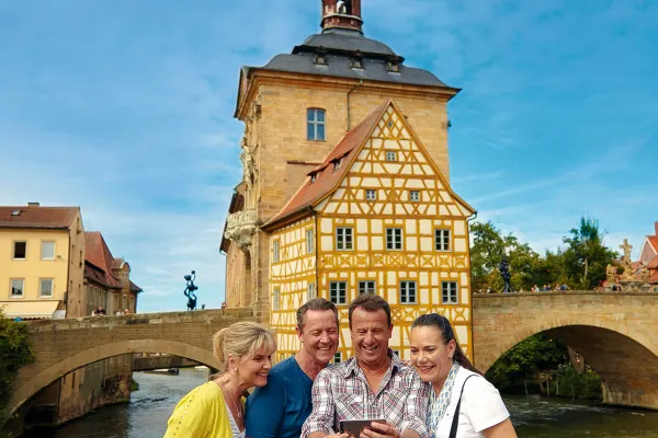 Middle-aged friends taking a selfie in front of a bridge and tower in Europe