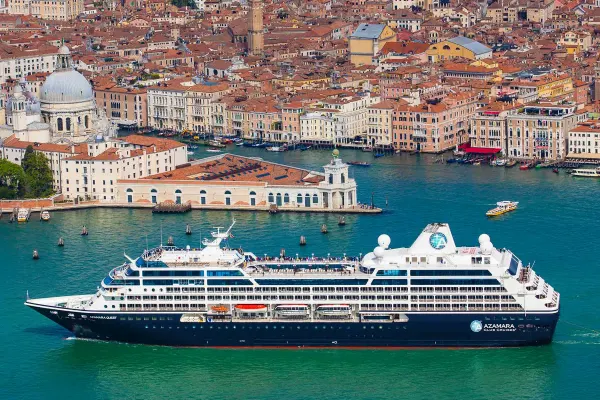 Drone shot of cruise ship with houses with orange roofs in the background