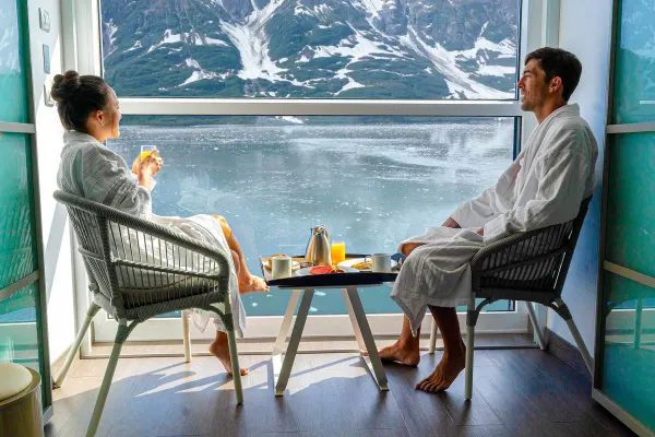 Two people sitting on their balcony looking at snow-capped mountains