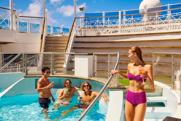 Four friends in pool drinking cocktails