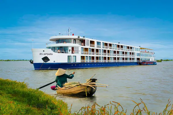 Travelmarvel cruise ship sailing past someone in a bamboo rowboat