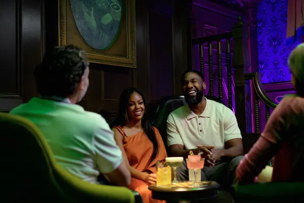 Smiling people having cocktails in a Haunted Mansion-themed bar