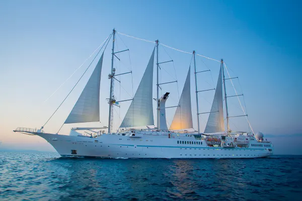 Cruise ship with sails on the ocean with an early sunset