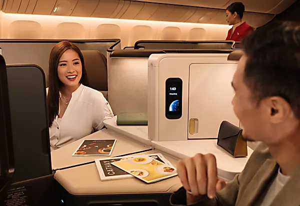 Cathay Pacific business class seat with two passengers chatting over the divider.