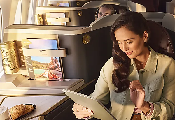 Etihad Airways spacious business class seat with passenger enjoying a coffee and snack. 