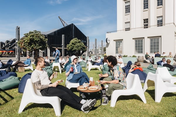 People in low, white chairs and beanbags relaxing and drinking on a sunny day