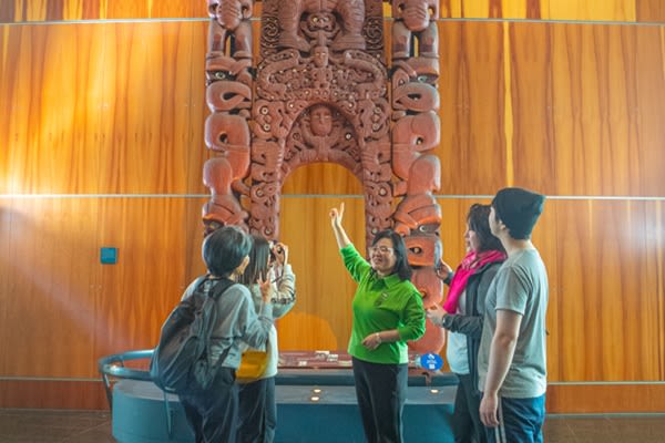 Tour group learning about a Māori statue
