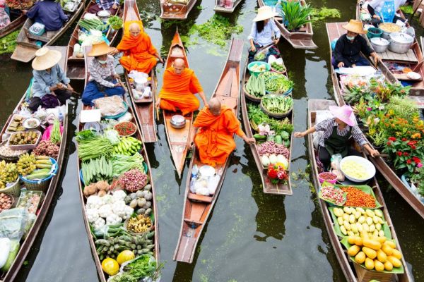 Canoe's carrying variety of fresh foods with monks in orange sit in separate canoe's