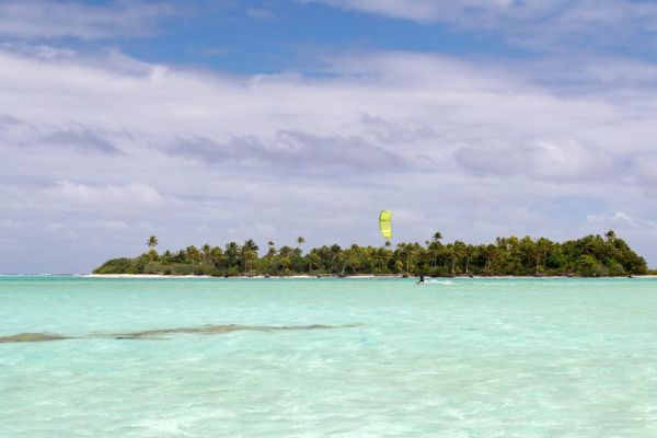 Kite surfer in background surfing clear waters in the Cook Islands