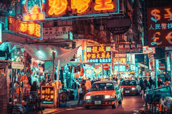 Street signs lite up as cars drive past in downtown Kowloon