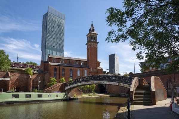 Old bridge over brown river with skyscraper in background