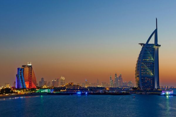 Dubai shoreline during dusk, city lights start turning on