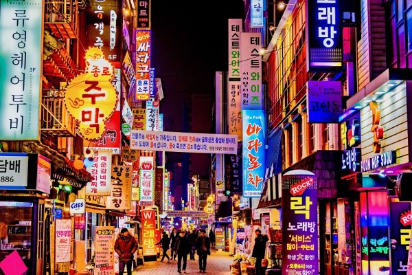people walking through lite up street signs during night time in Seoul