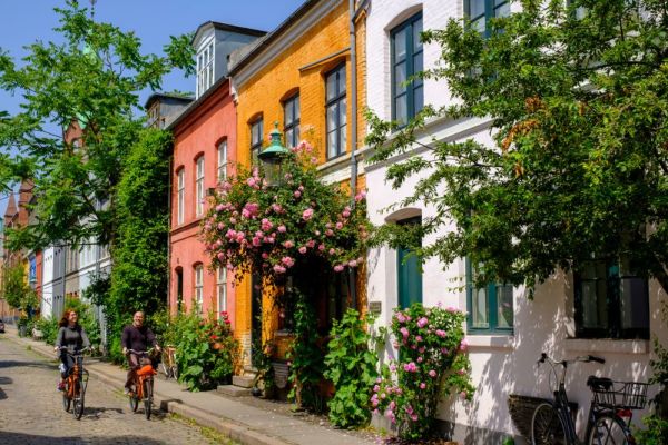 Couple cycling past colourful buildings and greenery