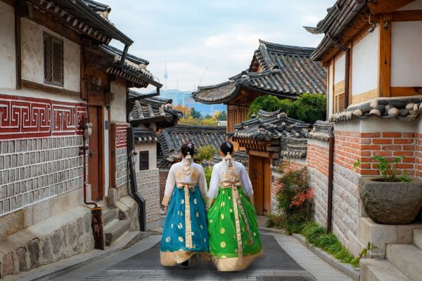 Two traditionally dressed females walking through traditional village in the streets of Seoul