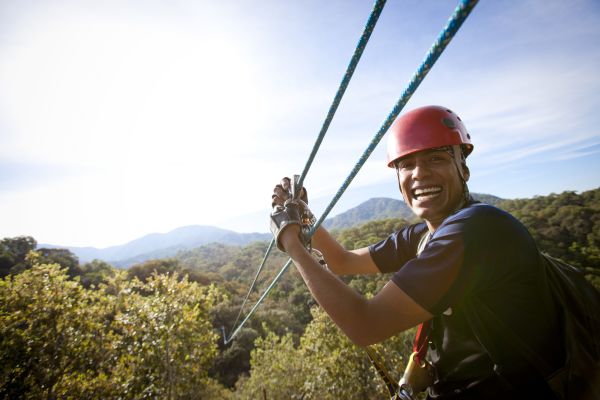 Man smiling looking back attached to a zip line