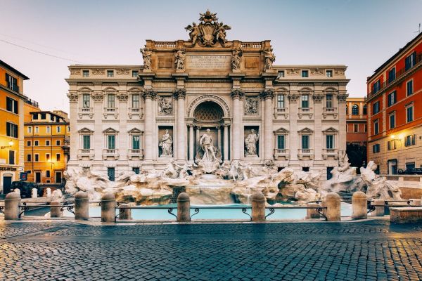 Front view of Trevi Fountain during dusk with lights turning on